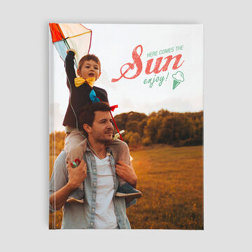 Un enfant est sur les épaules d'un adulte et tient un cerf-volant coloré. Ils sourient et profitent du jour ensoleillé.