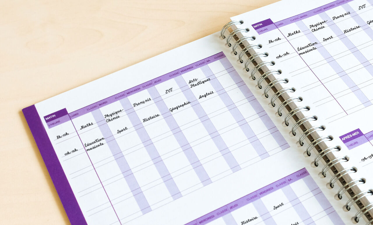 Une page ouverte d'un calendrier photo CEWE montre un tableau avec divers mois et notes