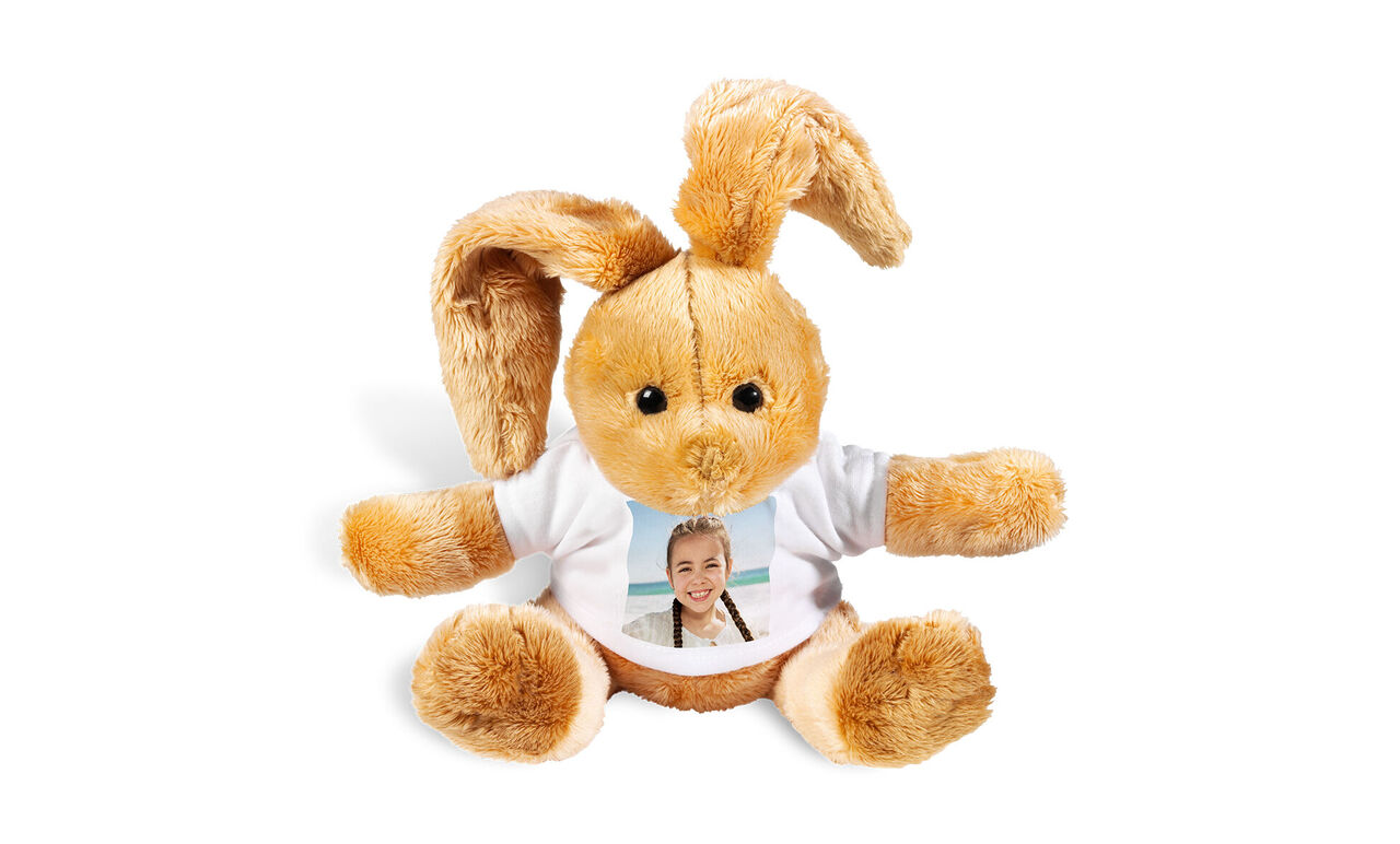 Un doux lapin en peluche avec des oreilles douces porte un T-shirt blanc avec une photo sur le devant.