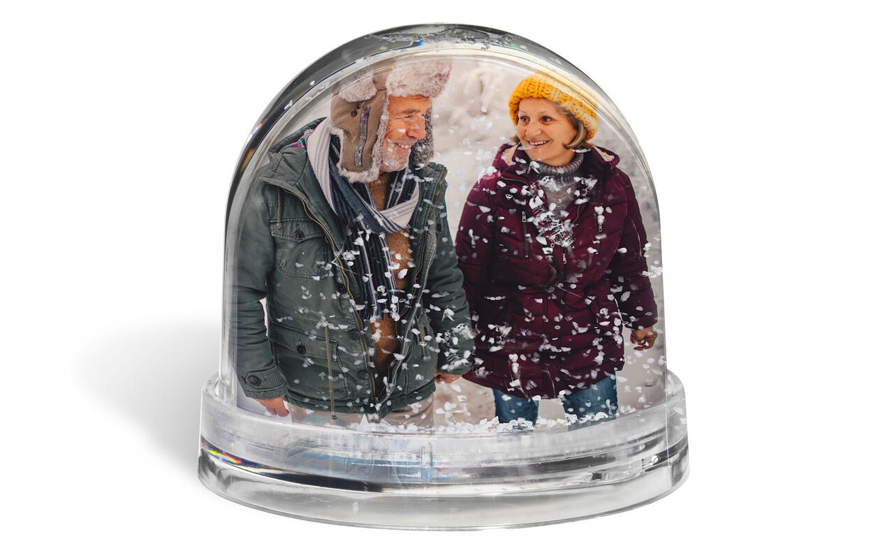 Deux personnes se tiennent dans une boule à neige, entourées de neige.