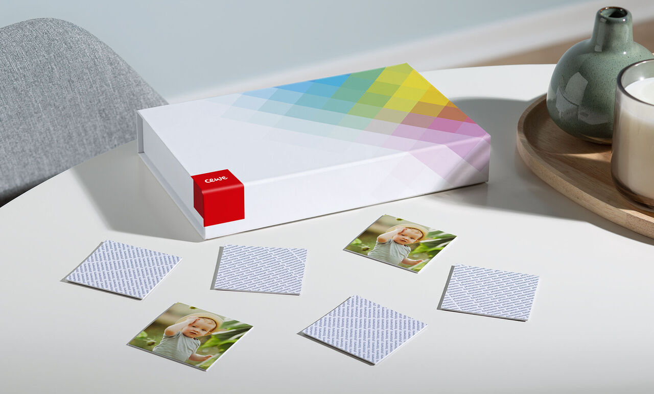 Livre photo CEWE sur une table, entouré de petites photos et d'un vase