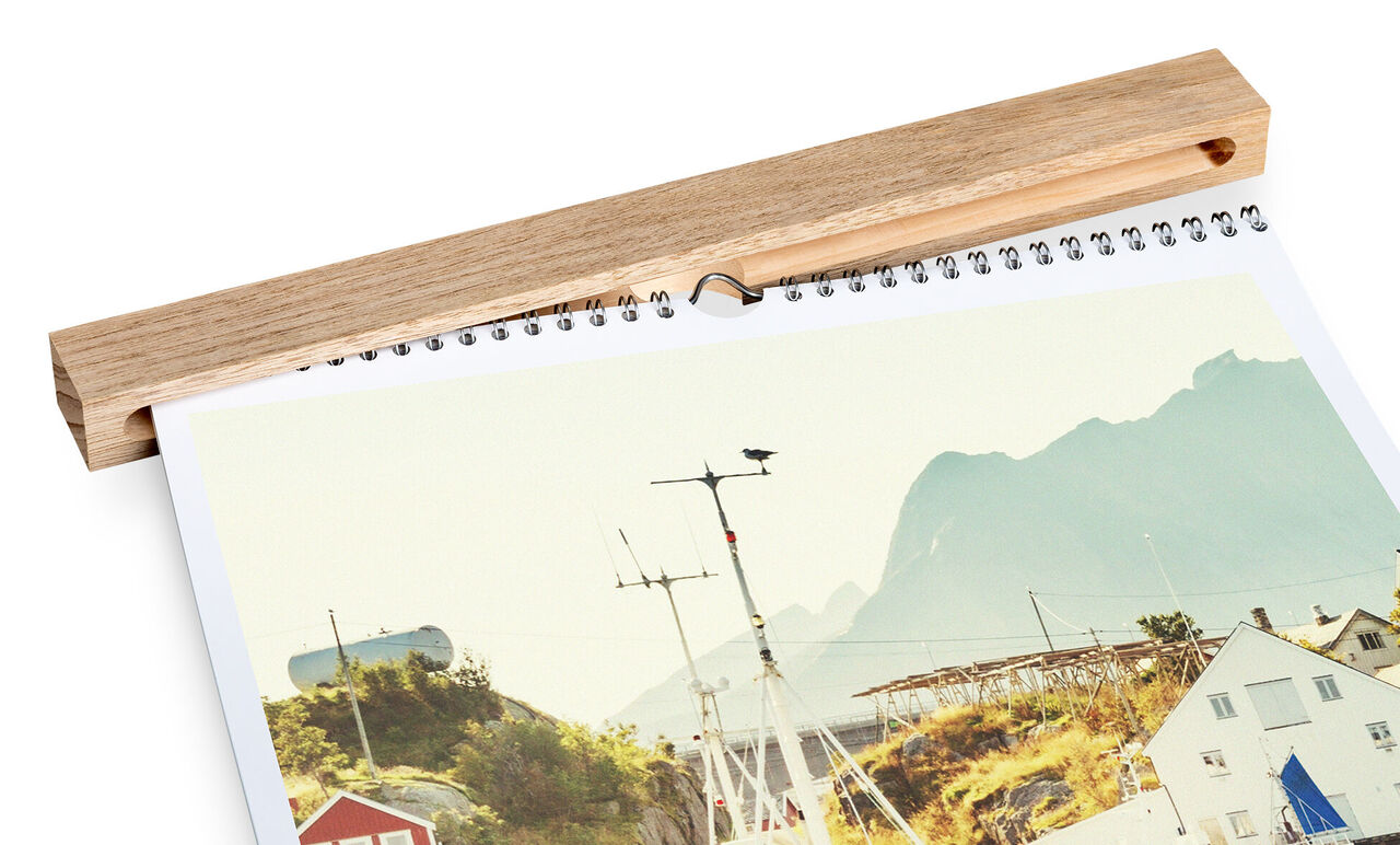 Un calendrier photo CEWE affiche un paysage côtier pittoresque avec des montagnes en arrière-plan.