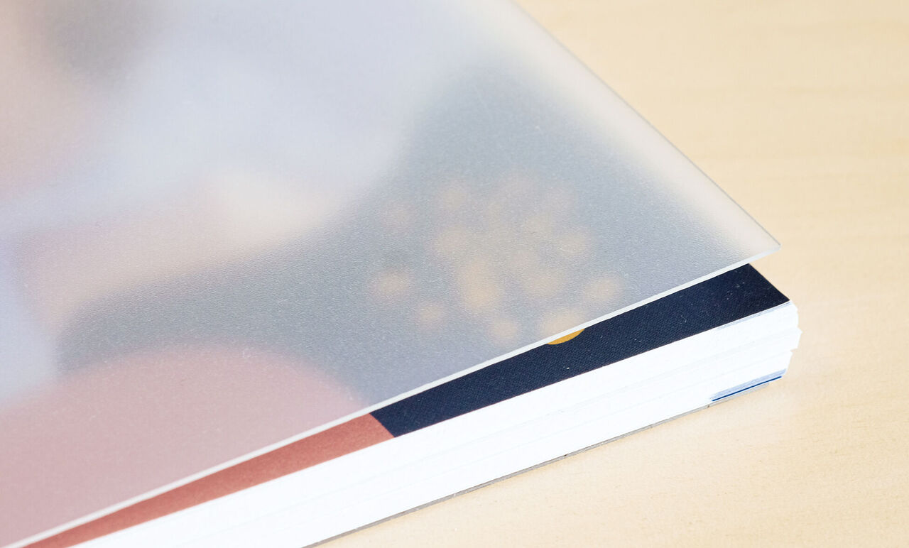 Gros plan d'un livre photo CEWE avec une couverture transparente et un intérieur coloré.