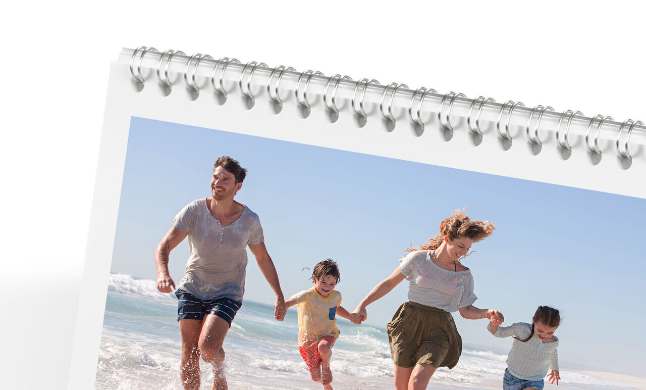 Une famille se promène joyeusement sur la plage, profitant du soleil. Calendrier CEWE.