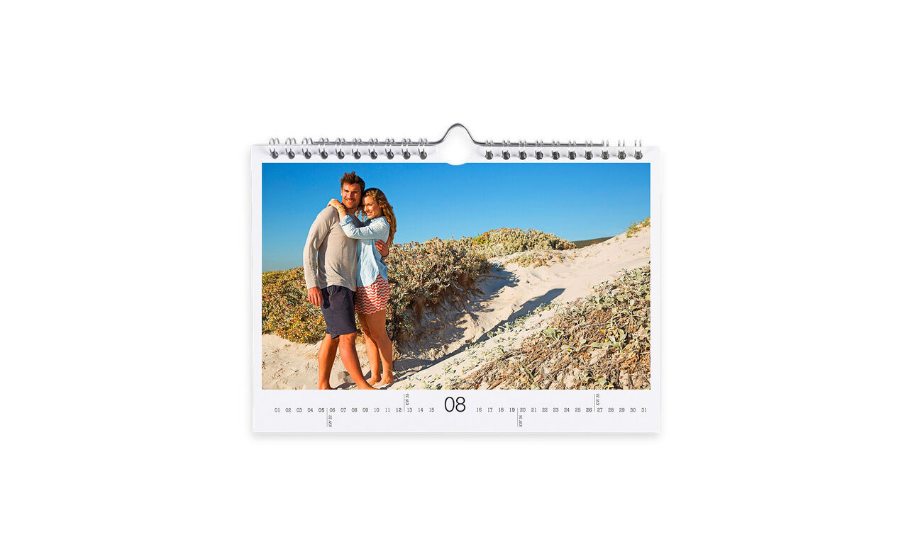 Un couple s'étreint joyeusement sur la plage en août. Ils sourient et profitent de cette belle saison.