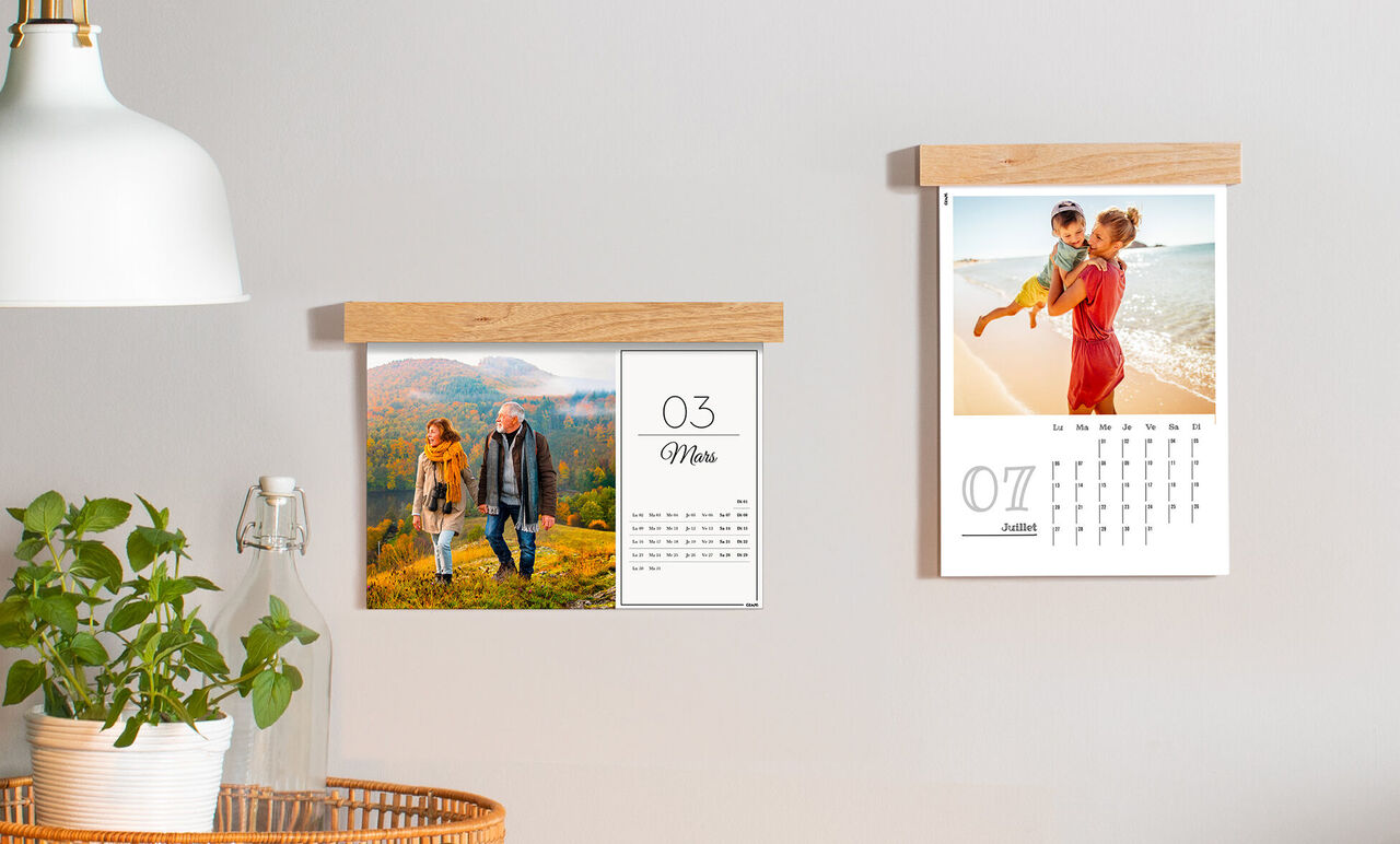 Deux calendriers photos CEWE accrochés au mur. Le gauche montre un couple dehors, le droit une famille à la plage.