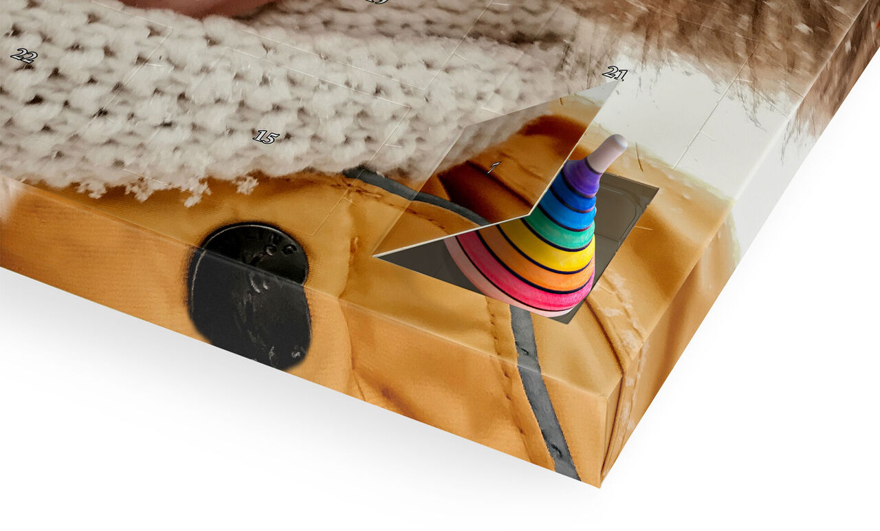 Une prise de vue détaillée d'un album photo avec un jouet empilable coloré sur un tissu jaune. Cette présentation colorée montre la polyvalence et la créativité d'un CEWE PHOTOBOOK.