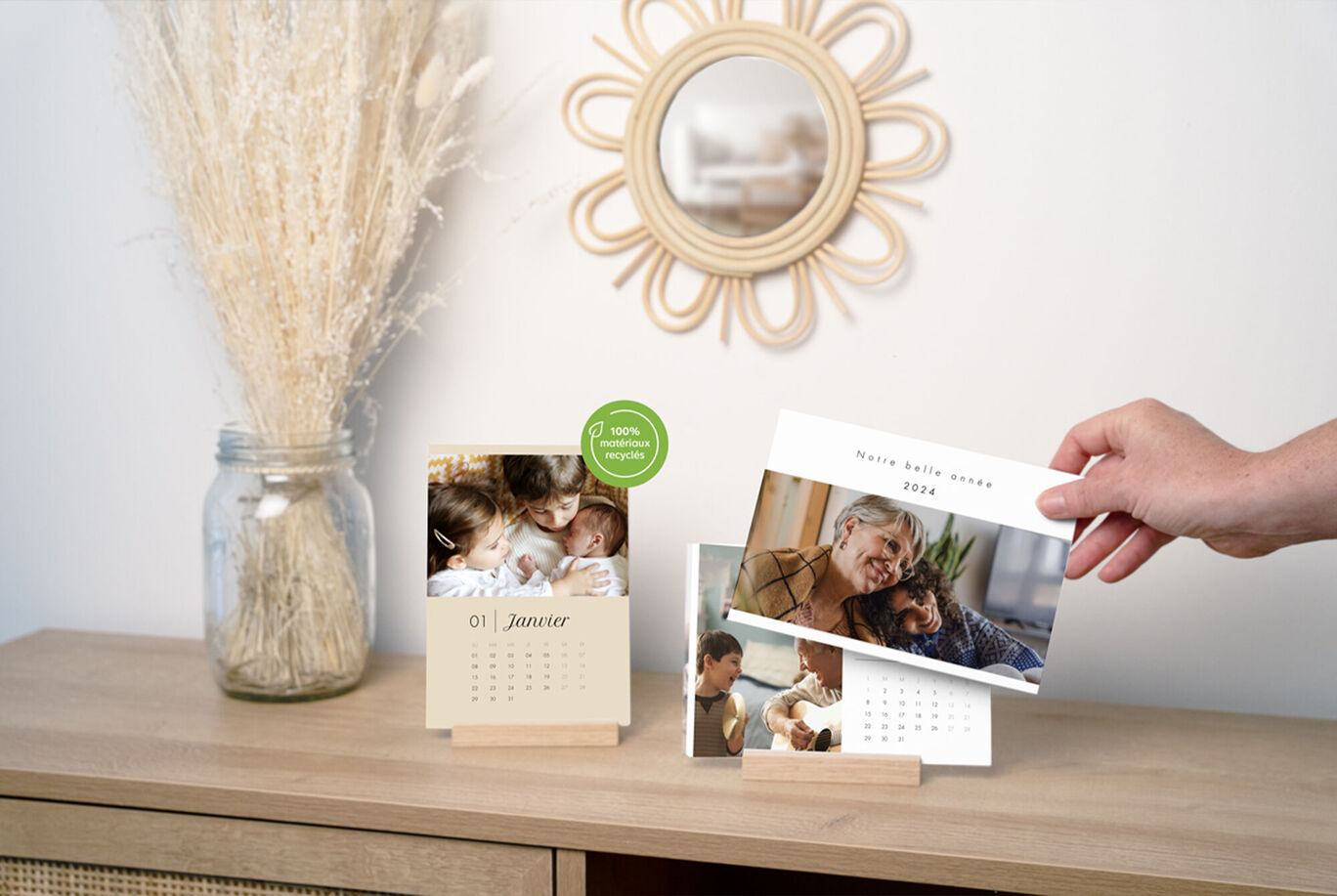 Un calendrier de bureau transparent est posé sur une surface de meuble. Le calendrier montre des photos de personnes et des années. Une main tient une page du calendrier.