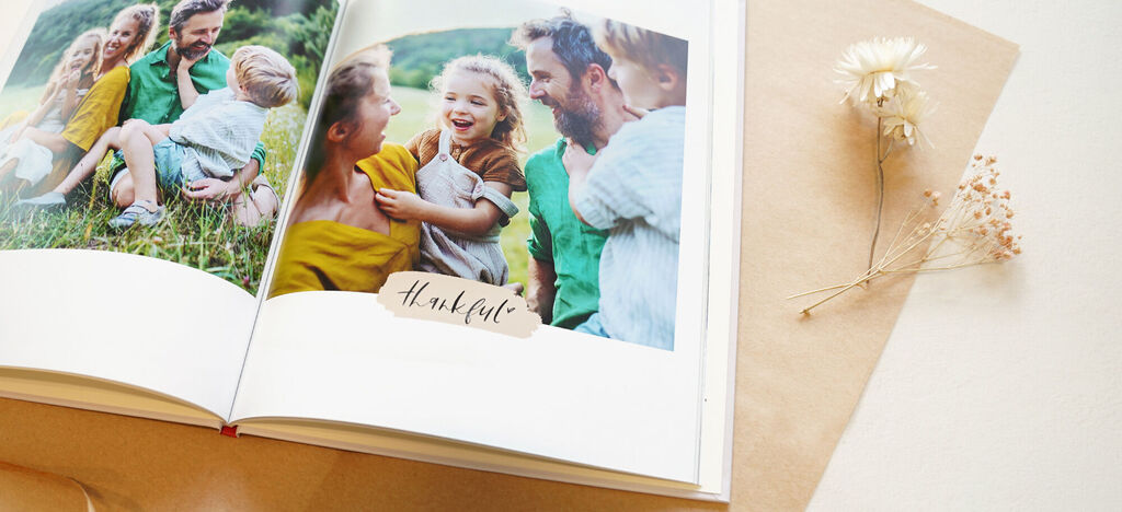 Un album photo ouvert avec des photos de famille à l'extérieur partageant des souvenirs, design avec "reconnaissant".