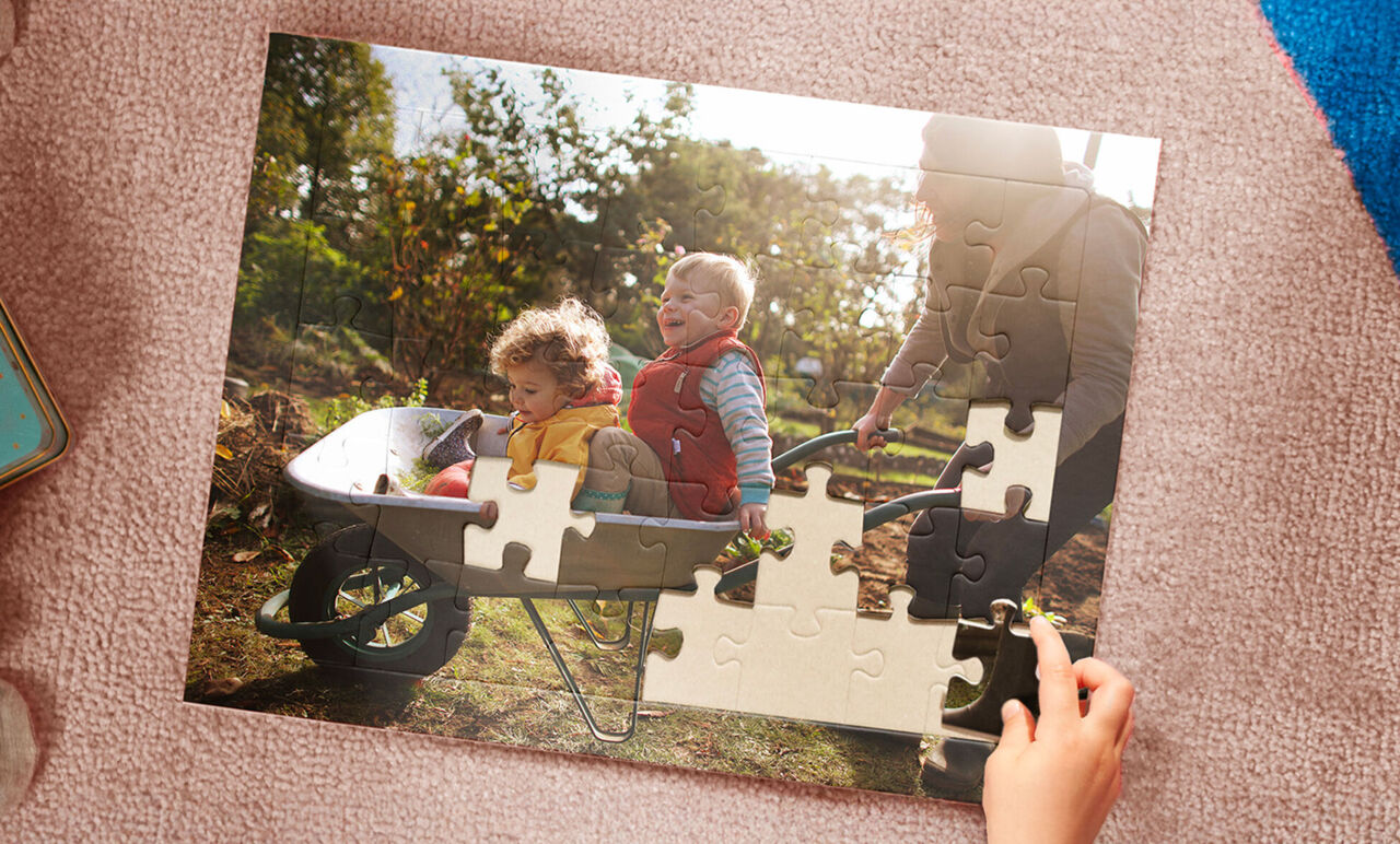 Enfant assemblant un puzzle montrant deux enfants avec une brouette au jardin