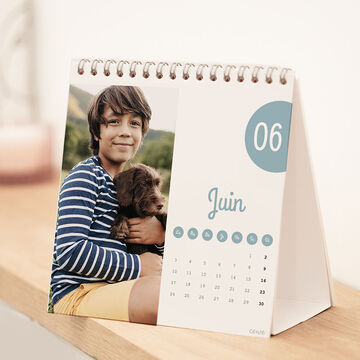 Un garçon tient un petit chien dans ses bras sur un calendrier de juin.