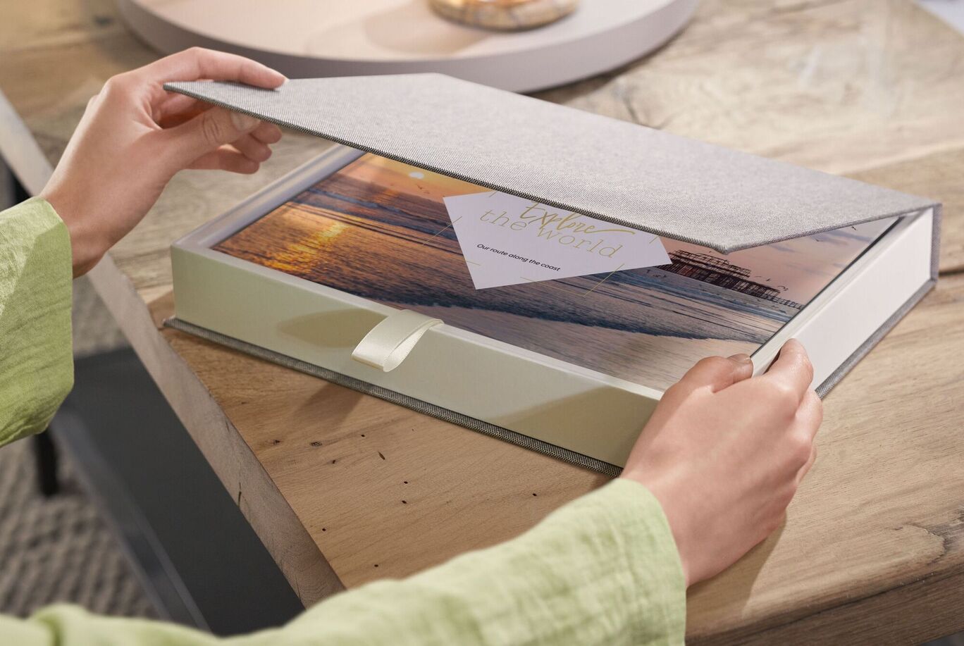 2 mains ouvrant une boîte cadeau avec un beau livre photo à l'intérieur