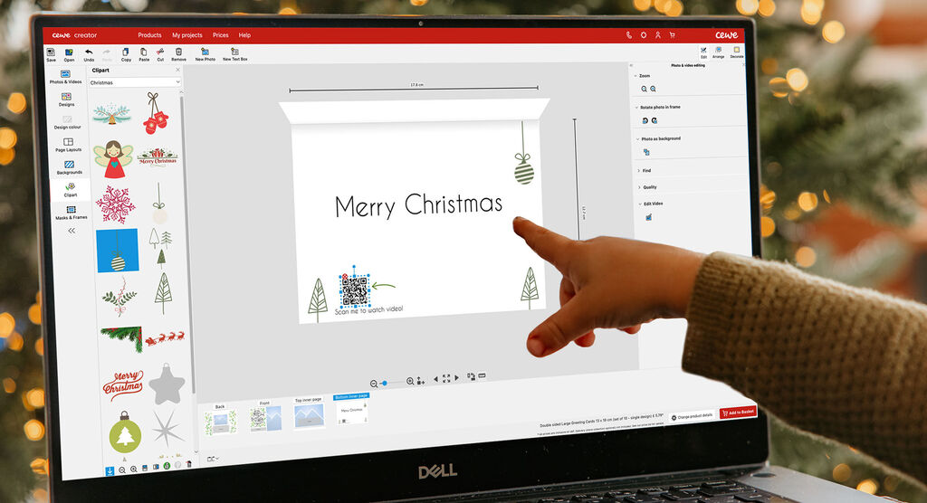 Quelqu'un crée une carte de Noël numérique. Éléments comme un sapin de Noël et des lumières brillantes visibles.