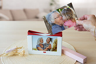 Une main tient une photo d'un enfant heureux riant avec une femme âgée.