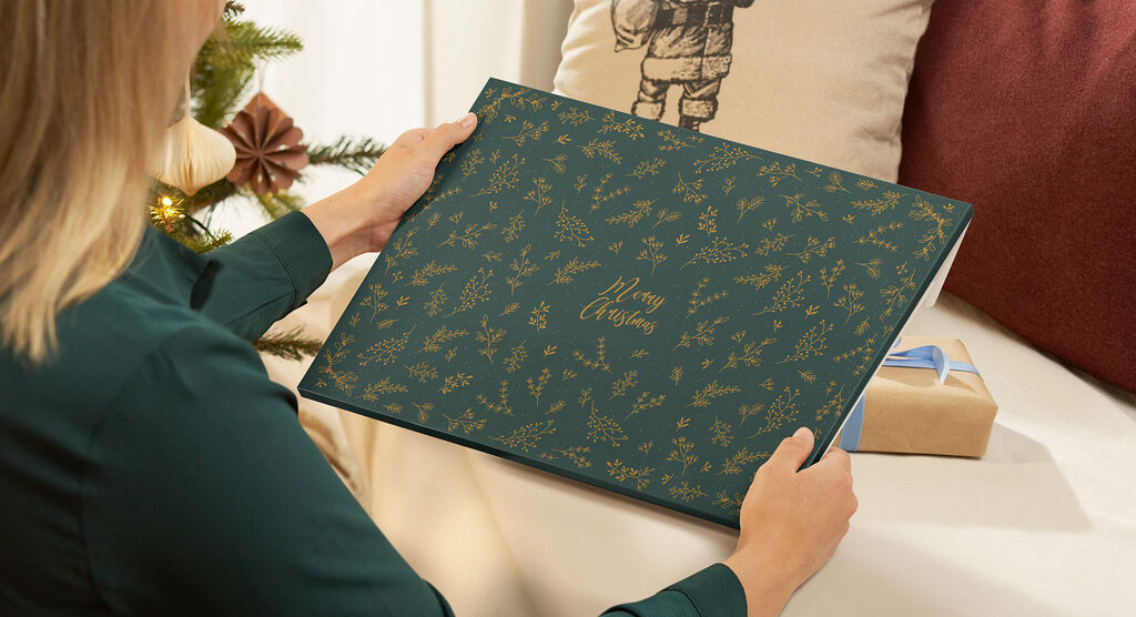Une personne tenant une pochette cadeau "Merry Christmas" pour calendrier photo