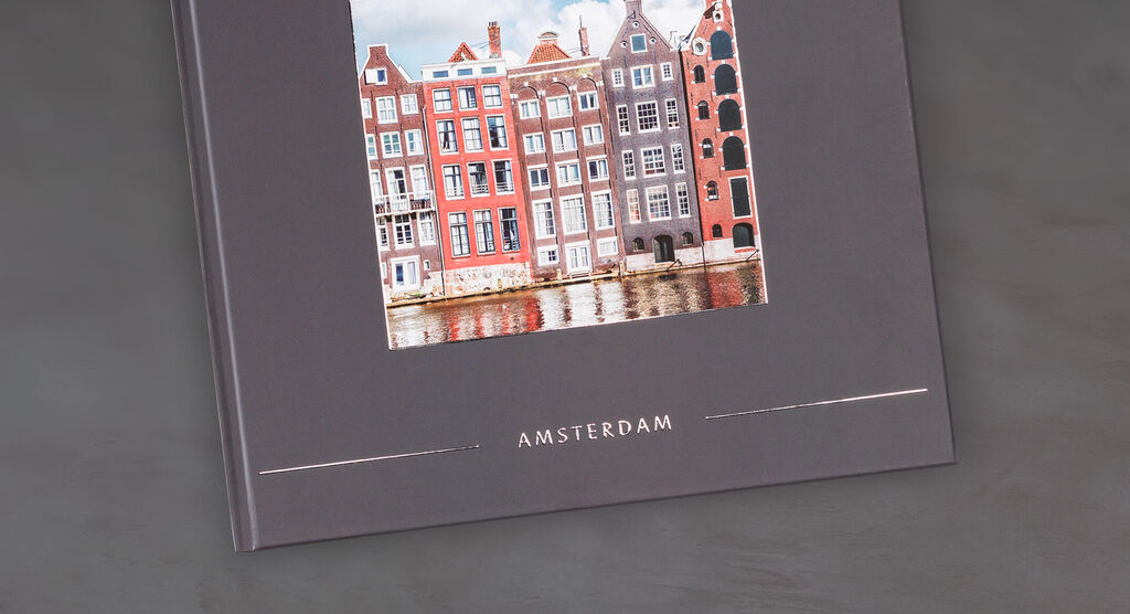 Un livre photo CEWE avec une belle photo de maisons colorées à Amsterdam sur un fond gris élégant