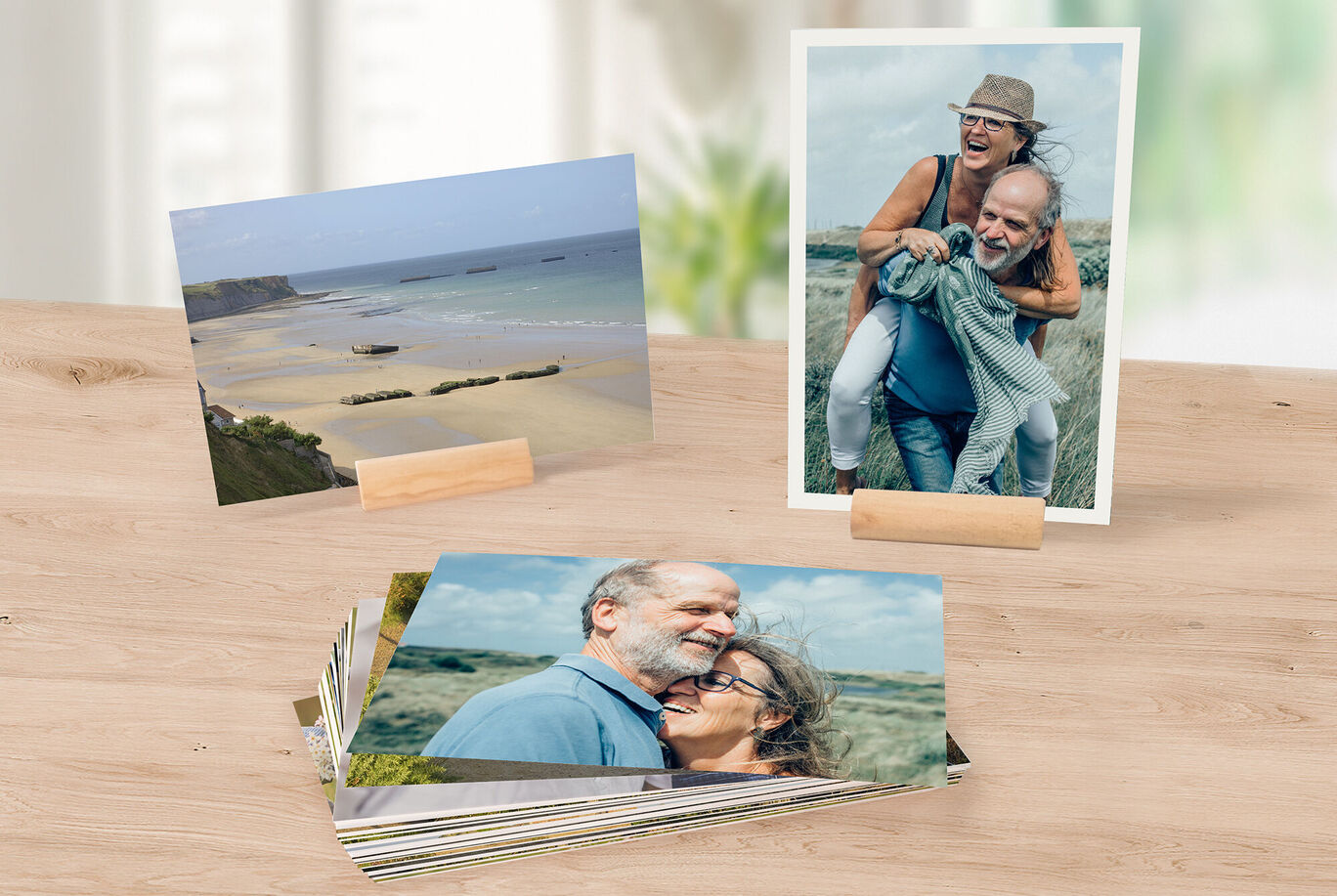 Trois photos sont sur une table en bois. Deux montrent de beaux paysages, une montre une personne avec un enfant. Elles sont joliment disposées.