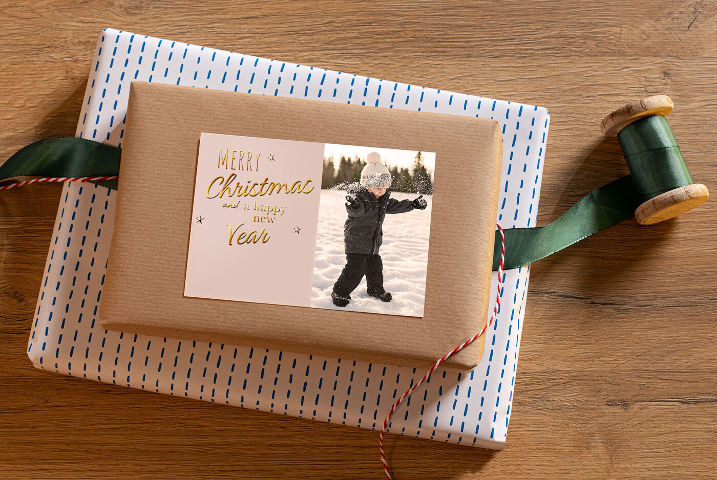 Un cadeau soigneusement emballé dans un design festif sur une table en bois, entouré de ruban cadeau et d'une bobine en bois.