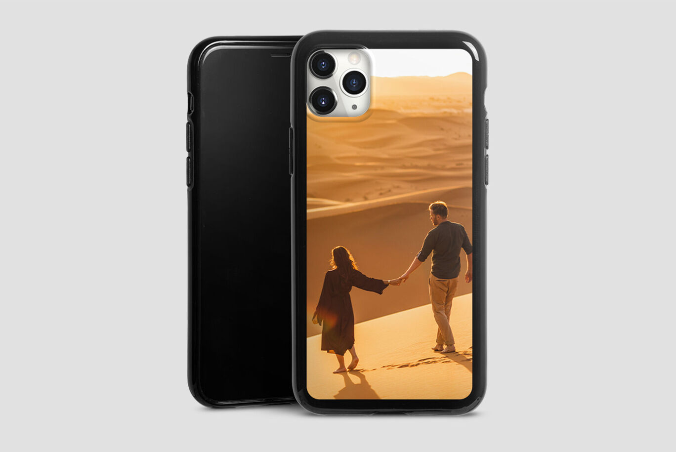 Un couple marchant main dans la main sur des dunes de sable au coucher du soleil