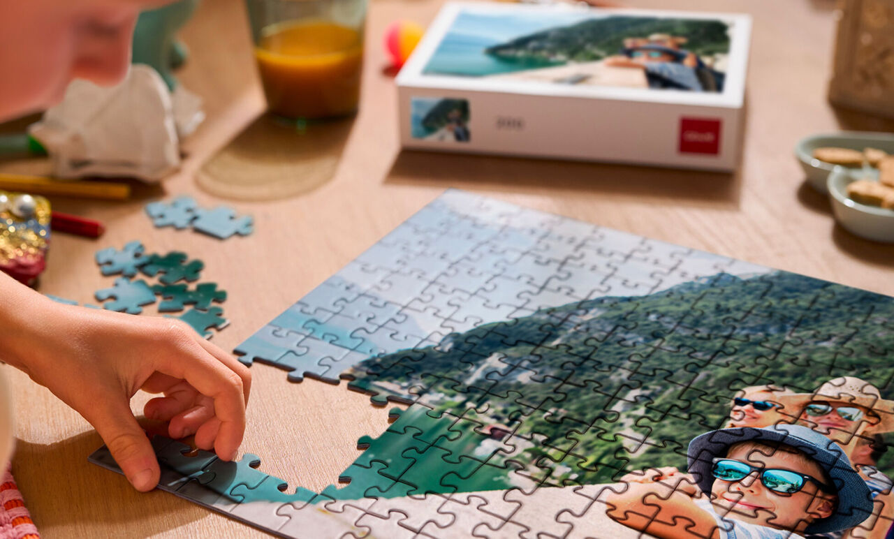 Mains assemblant un puzzle personnalisé de voyage, avec sa boîte en arrière-plan