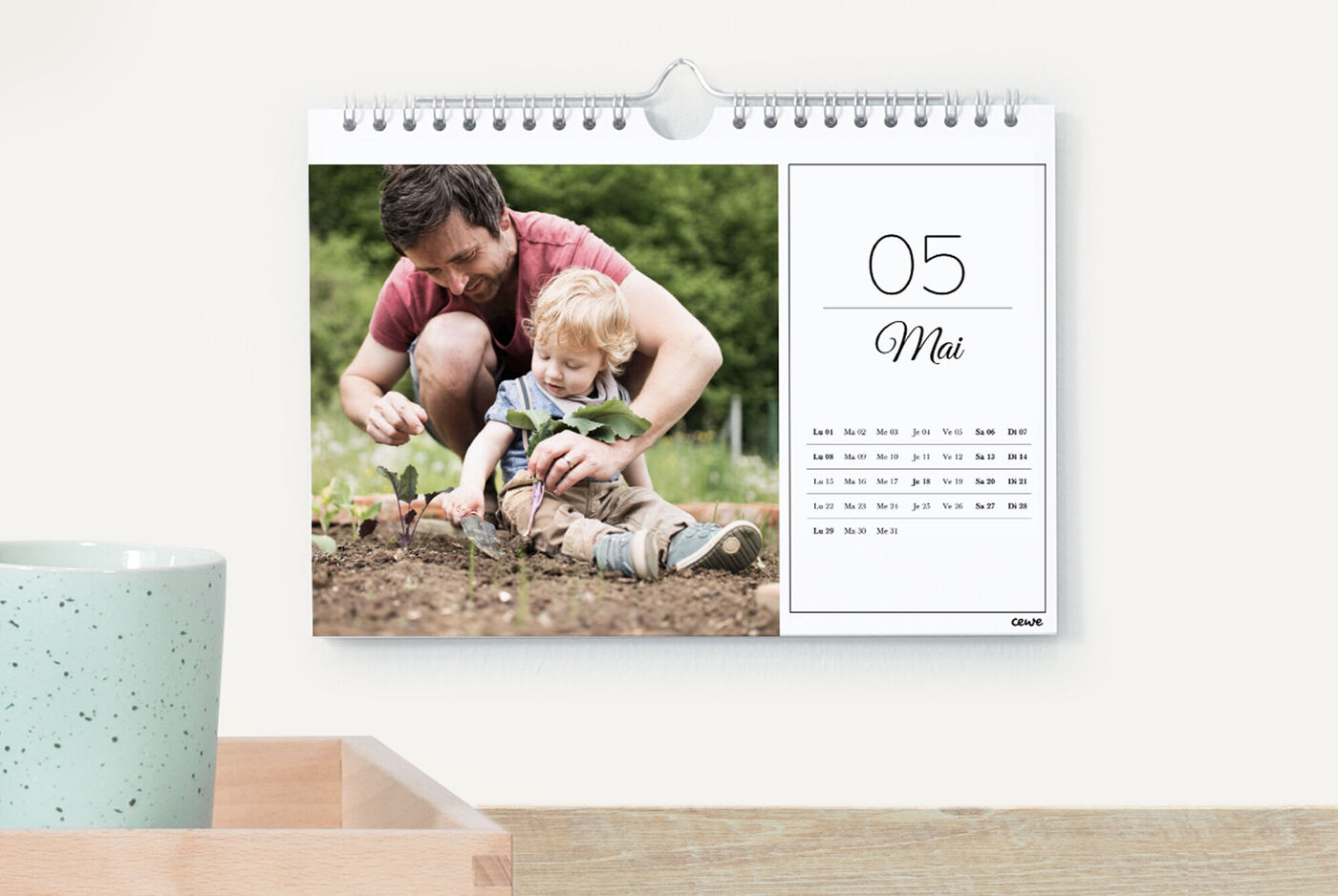 Un père et son enfant plantent des semis dans le jardin, visible dans un calendrier CEWE pour mai.