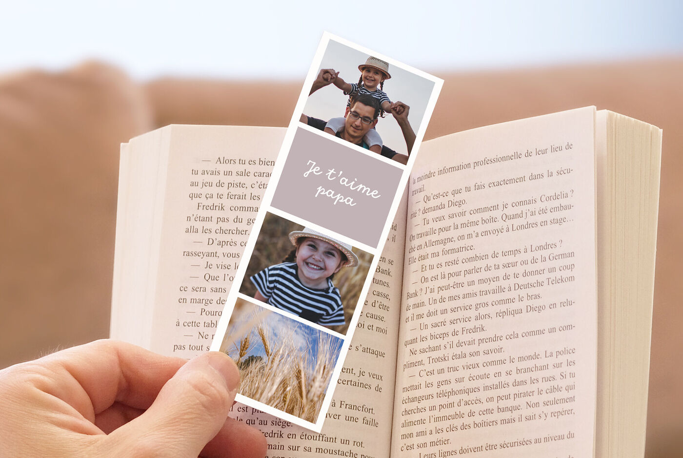 Un marque-page avec des photos adorables d'un enfant et d'un paysage, tenu dans un livre ouvert.