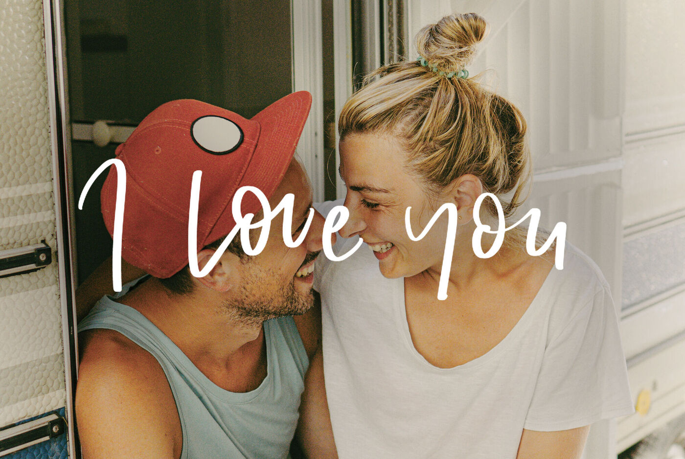 Un couple assis ensemble dans un camping-car profite d'un beau moment. Texte 'I Love You' au-dessus de l'image.