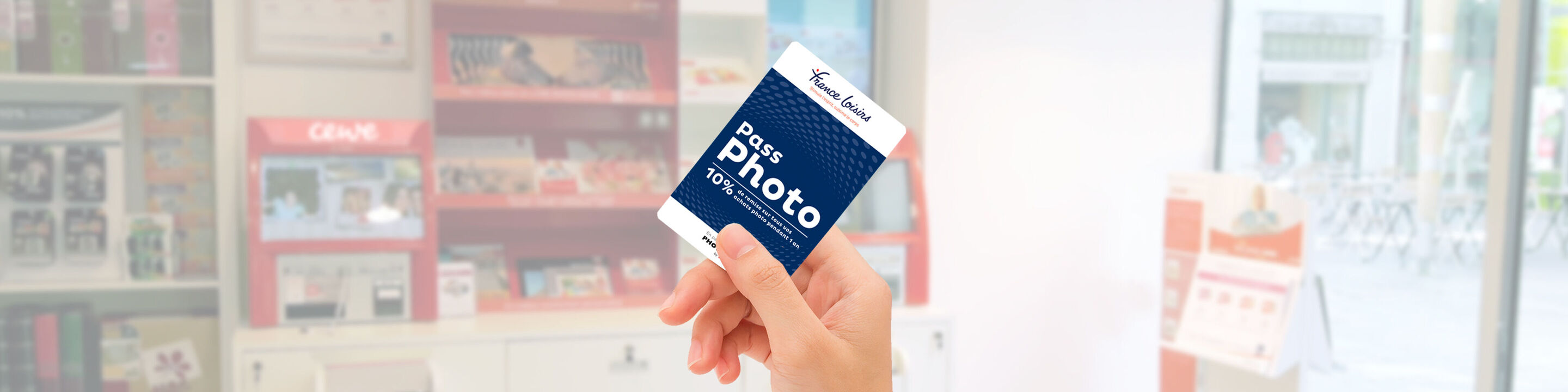 Une main tient un bon CEWE pour cartes photo dans un magasin lumineux.