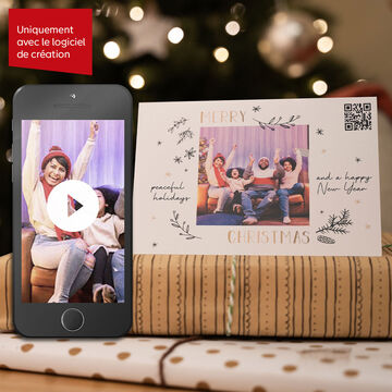 Un téléphone montre une vidéo à côté d'une carte de fête avec 'Joyeux Noël'