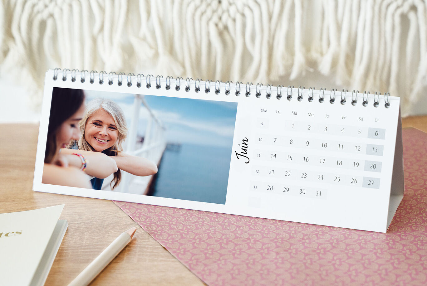 Vue sur une table avec un calendrier pour le mois de juin, un carnet et un stylo à côté.