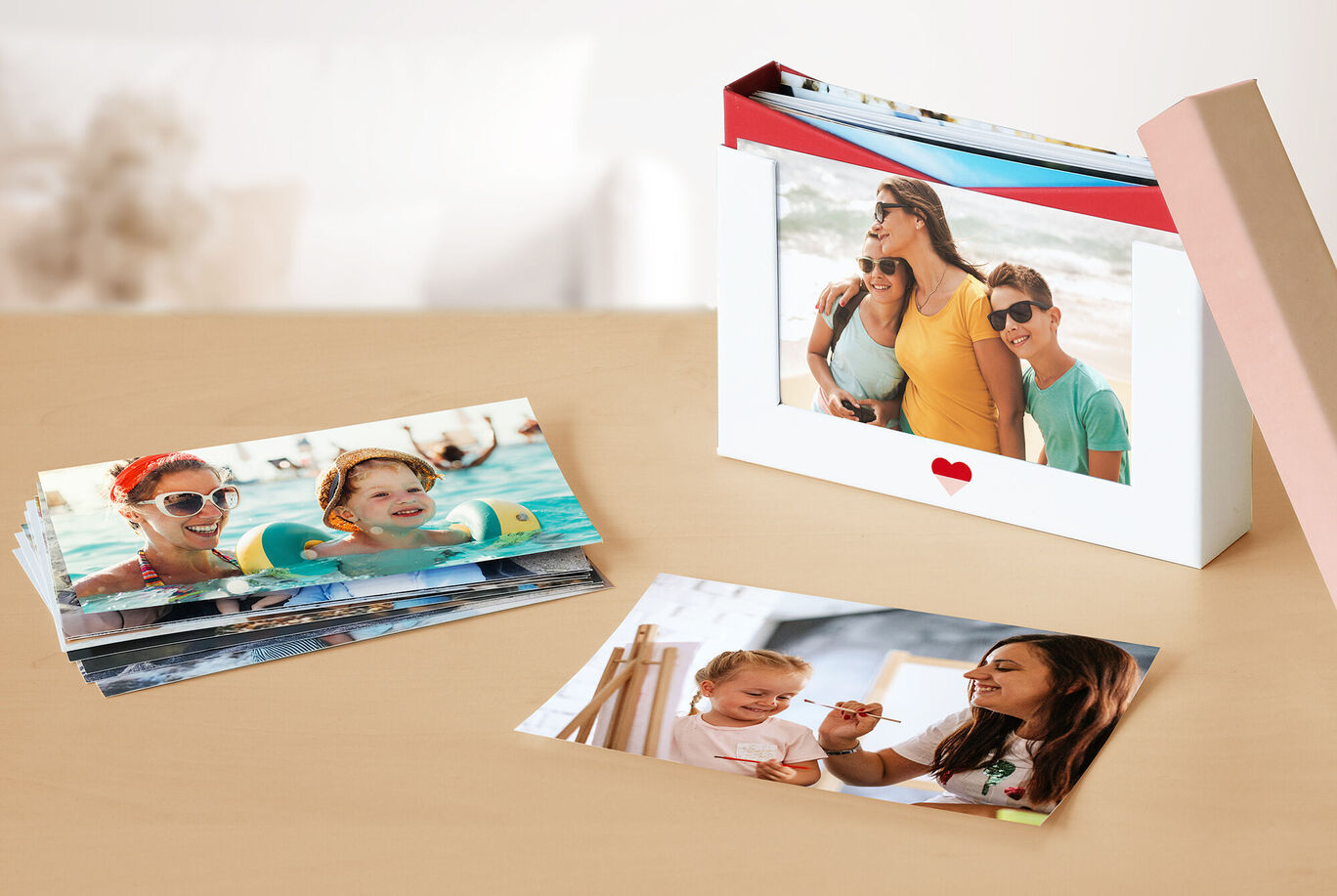 Des photos colorées sont sur une table, un livre photo CEWE à côté montre une sortie en famille.