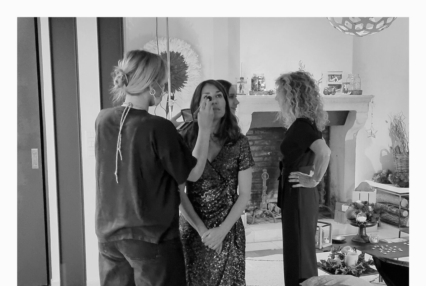 Trois femmes préparent une séance photo dans une pièce lumineuse.