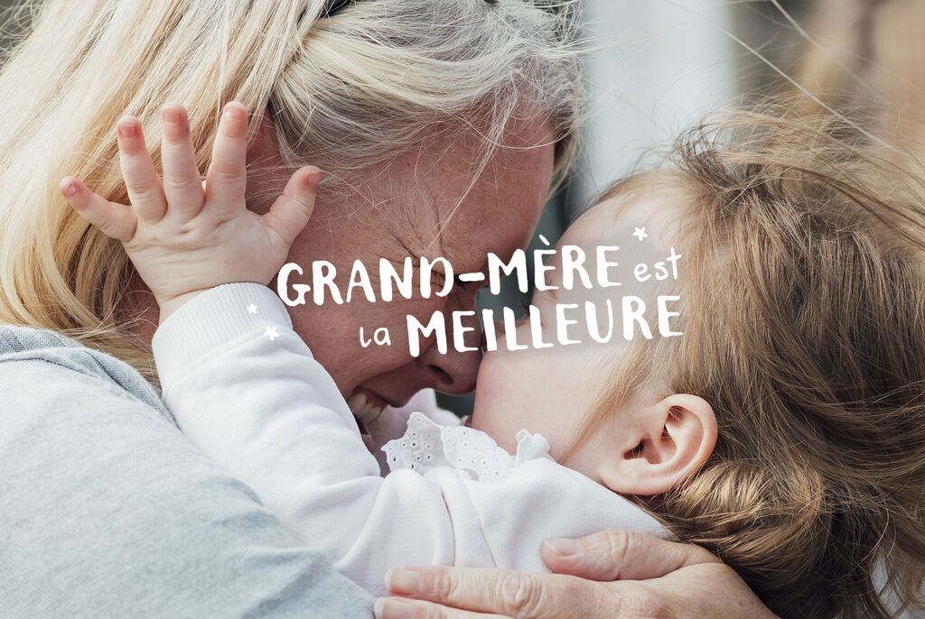 Une grand-mère enlace affectueusement son petit-enfant. Tous deux rient de bonheur.