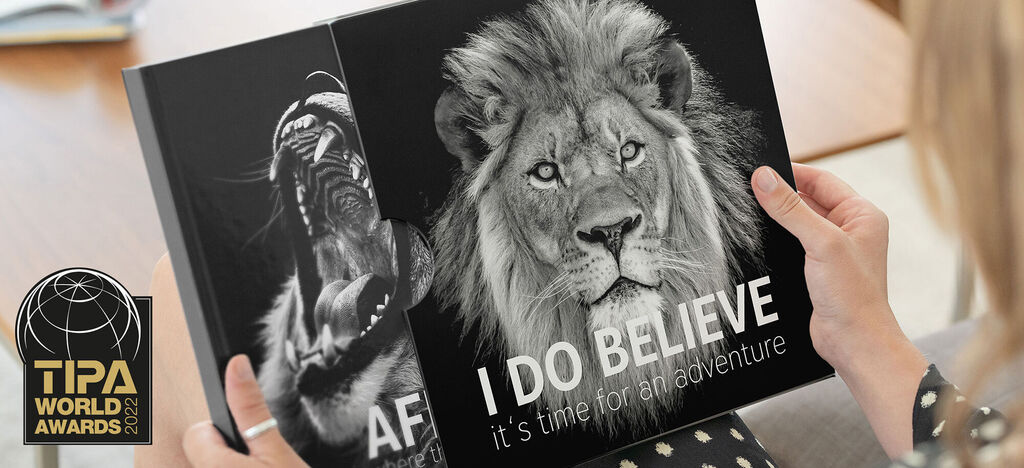 Une personne tient un CEWE ALBUM PHOTO avec une couverture de lion.