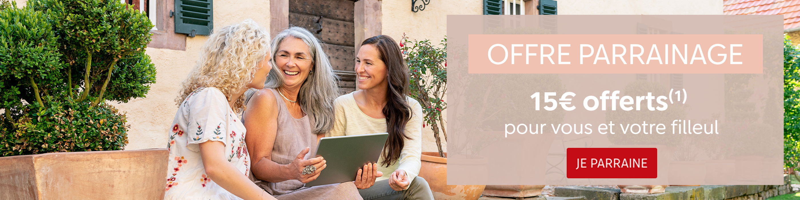 Trois femmes assises dehors, regardant une tablette, dans un endroit accueillant.