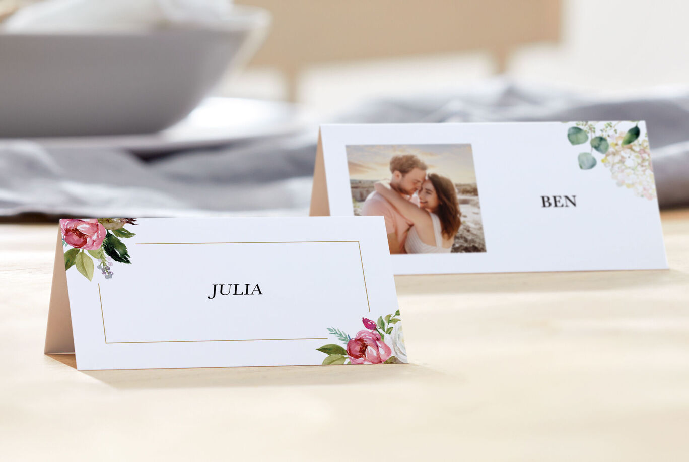 Deux cartes de table avec les noms Julia et Ben, entourées de fleurs.