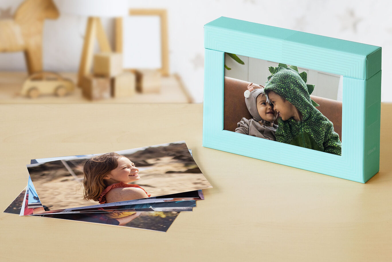 Une magnifique boîte photo avec des photos sur une table. La boîte a une couleur menthe fraîche et montre une image d'un enfant avec une couverture. À côté, il y a de belles captures photographiques sur la table.