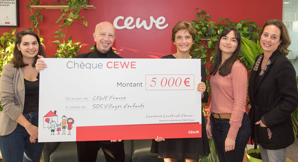 Un groupe de personnes présente un grand chèque de 5000 euros avec l'inscription 'Chèque CEWE'.