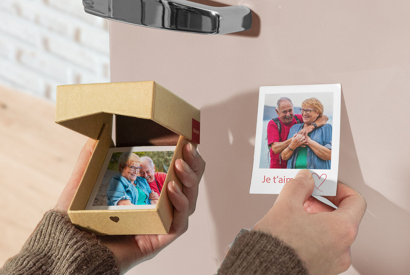 Une personne tient une petite boîte cadeau avec des cartes photo, montrant une autre carte. La scène dégage joie et connexion.