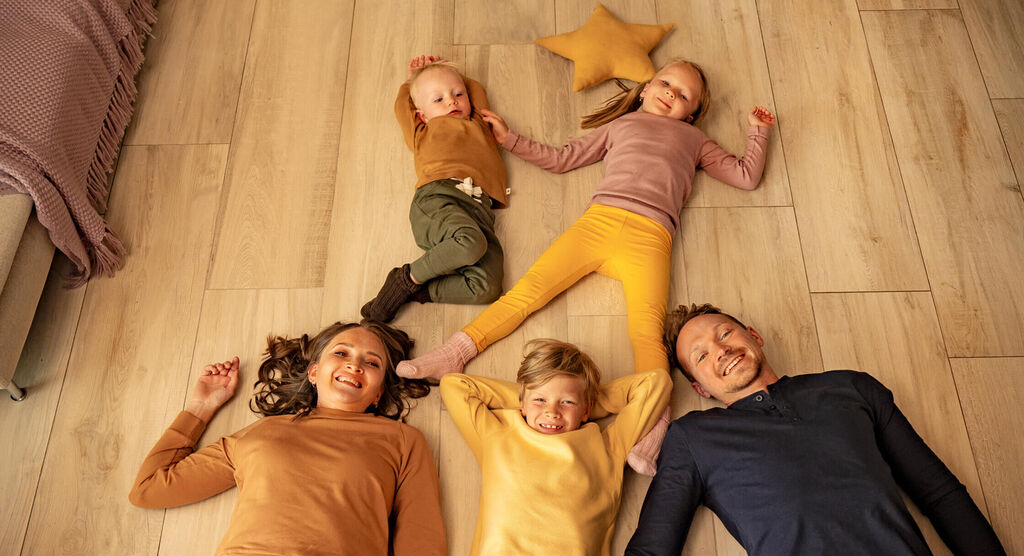 Une famille heureuse est allongée sur le sol, profitant de leur temps ensemble, entourée d'un coussin en forme d'étoile.