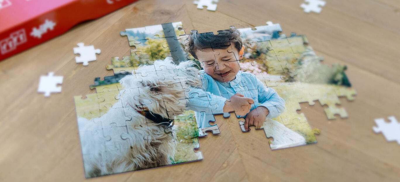 Un puzzle à moitié fini avec un chien et un enfant sur une table en bois.