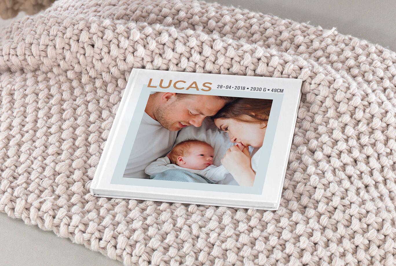 Un album photo CEWE joliment conçu avec nom et date, sur un tissu douillet.