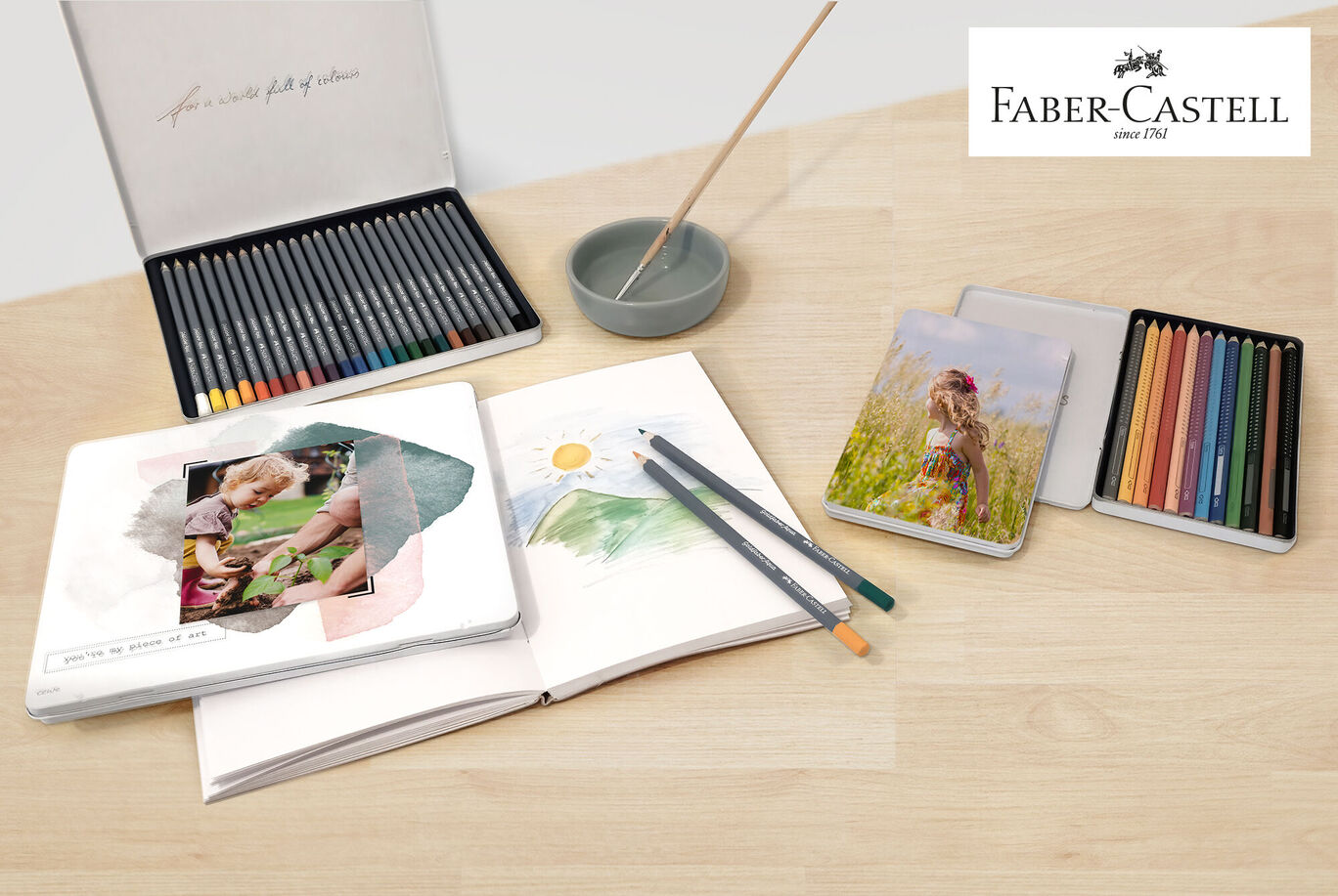 Une table créative avec des fournitures Faber-Castell, un album photo et des images.