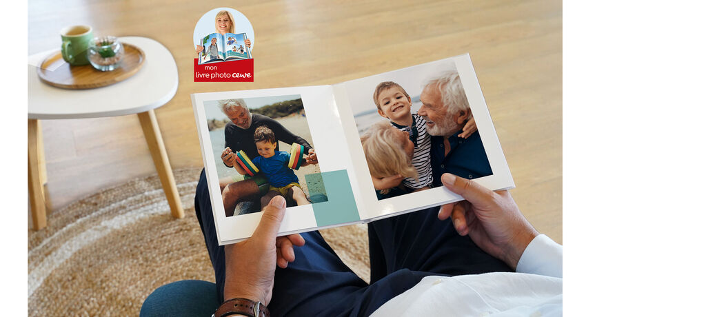 Une personne regarde un album photo CEWE ouvert, avec des photos de la famille et des amis. L'environnement est lumineux et accueillant.