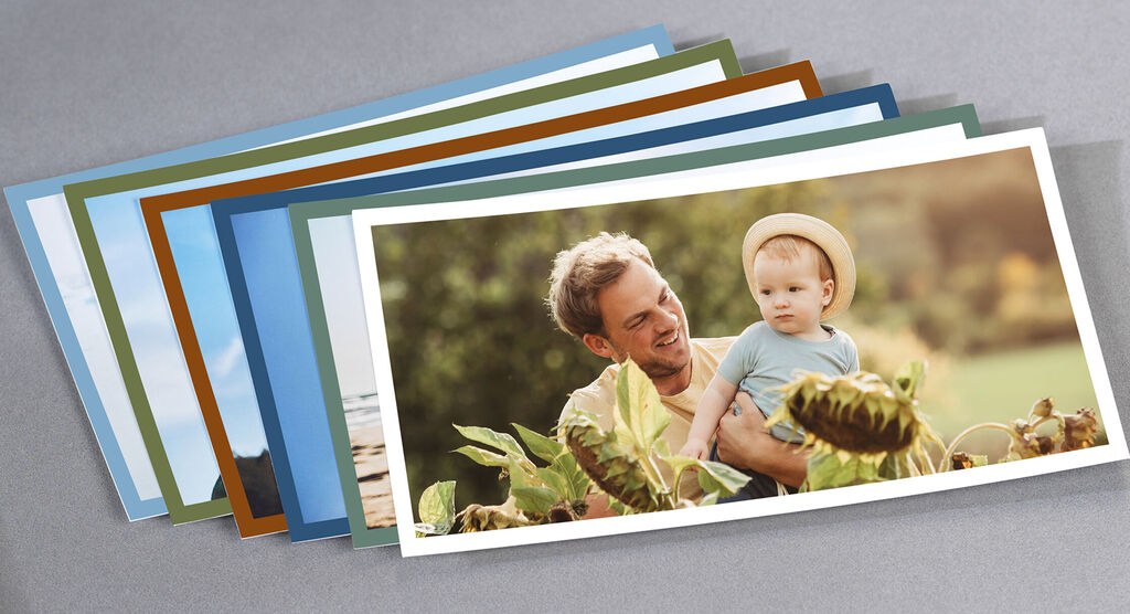 Un père souriant tient son enfant dans ses bras, entouré de plantes. Il dégage joie et amour.