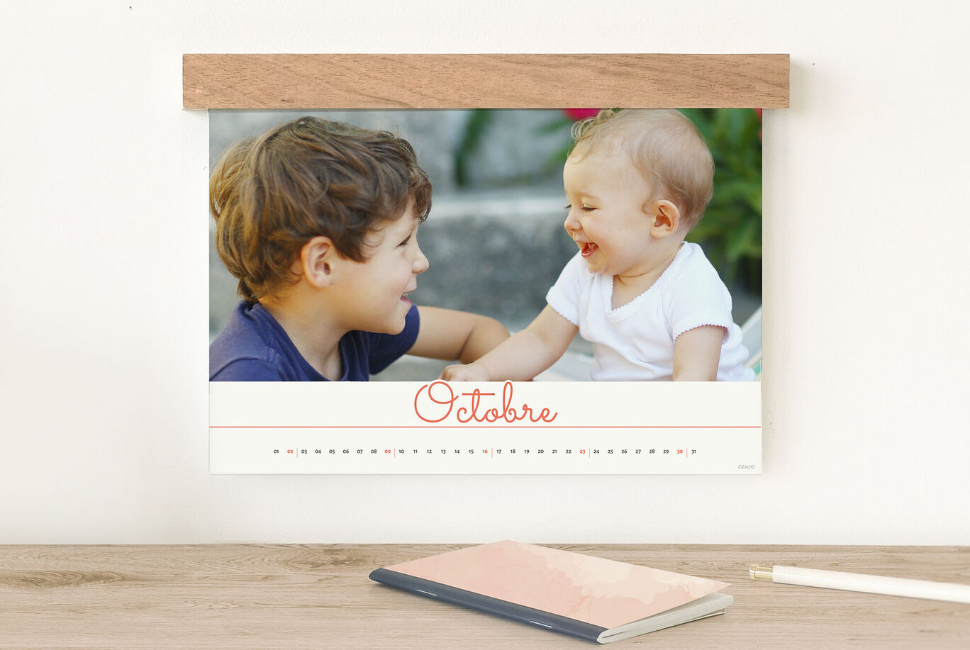 Un garçon et un petit enfant sont assis ensemble et sourient. Le calendrier montre le mois d'octobre, avec un arrière-plan vert.