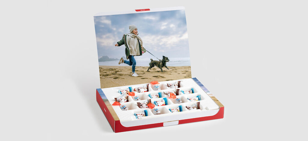 Un enfant joyeux court avec un chien sur la plage, une boîte de bonbons colorée au premier plan.