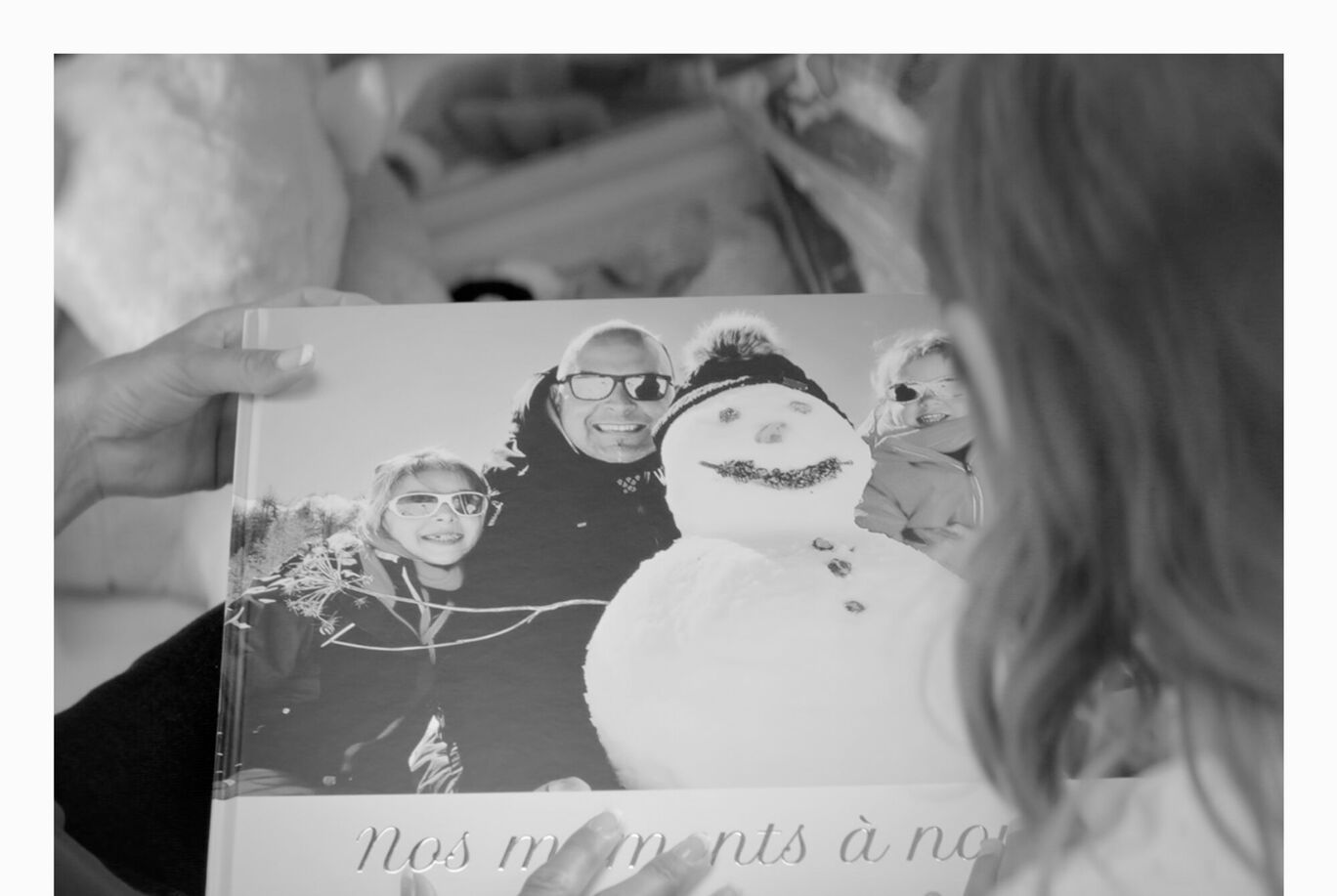Une personne feuillette un album photo d souvenirs d'hiver et un bonhomme de neige