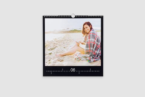 Une personne assise sur la plage avec un foulard à carreaux, lisant un livre