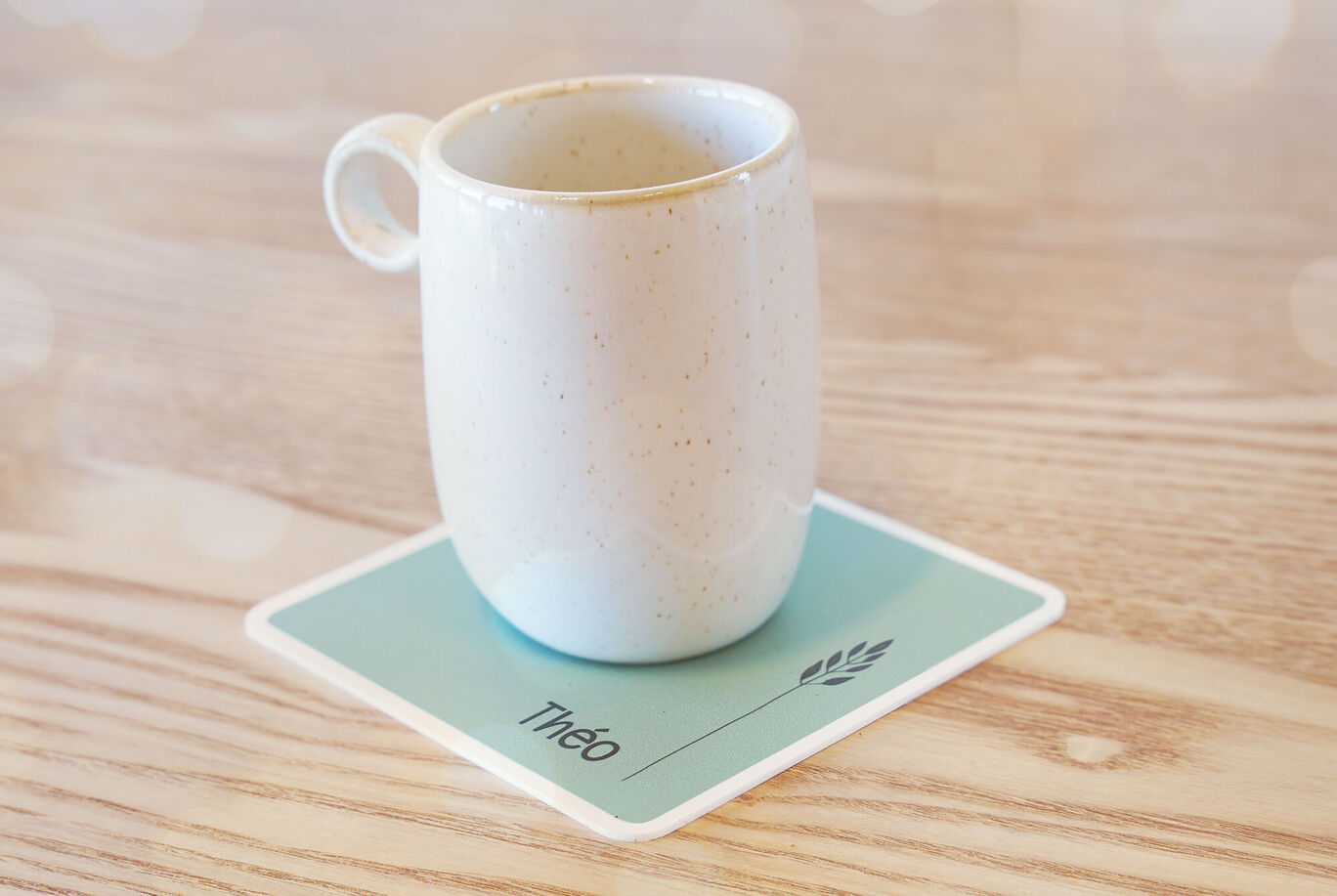 Mug blanc sur un sous-verre avec le nom "Théo".